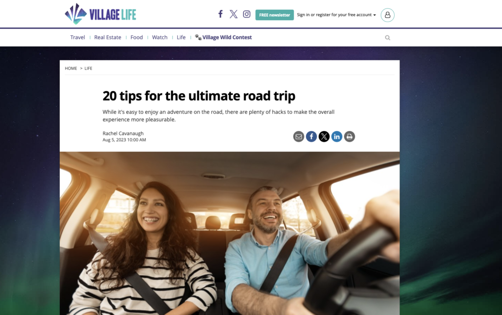 A couple is seen laughing in the car on a road trip in a photo at the Village Life website.